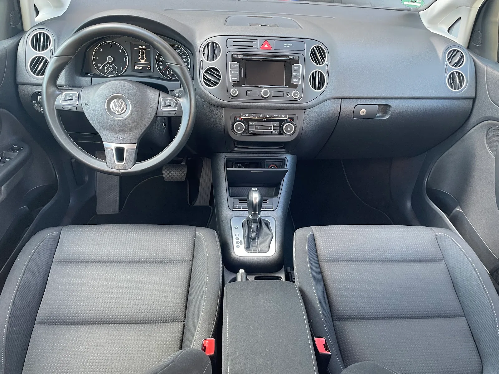 Frontal fotografiertes Cockpit eines VW Golf Plus mit sauberem Armaturenbrett, Lenkrad, Mittelkonsole und fleckenfreien Stoffsitzen.