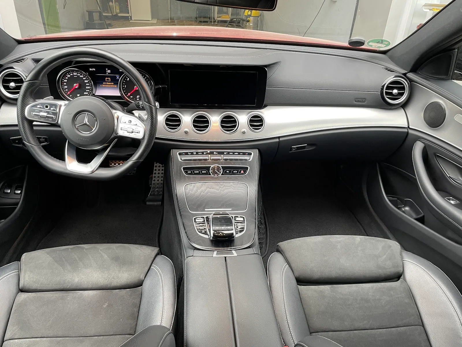 Gereinigtes Cockpit einer Mercedes E-Klasse mit Lenkrad, Doppel-Display, Mittelkonsole in Klavierlack und Alcantara-Sitzen.