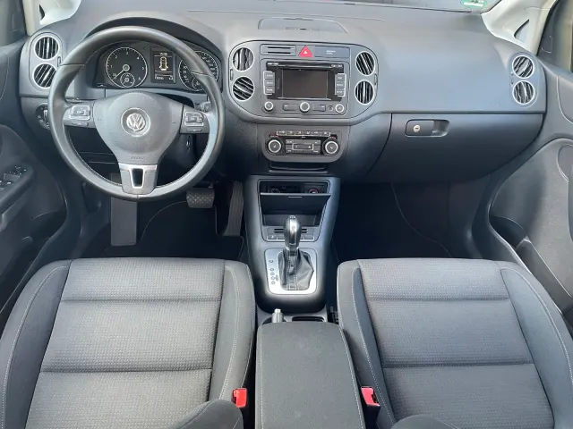 Frontal fotografiertes Cockpit eines VW Golf Plus mit sauberem Armaturenbrett, Lenkrad, Mittelkonsole und fleckenfreien Stoffsitzen.